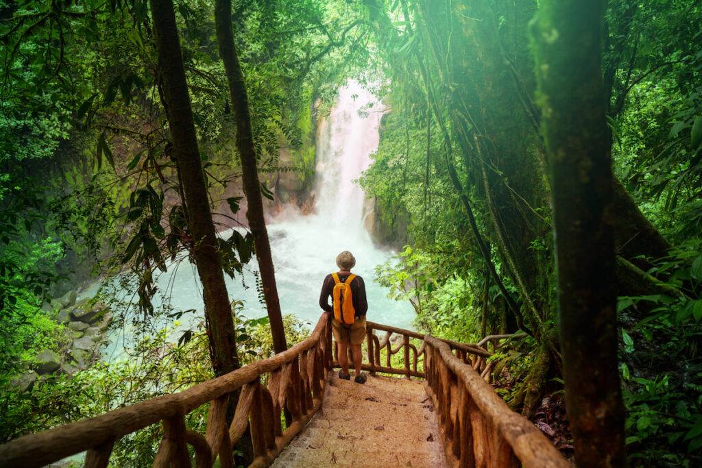 Hombre observando una cascada de agua turquesa en Costa Rica