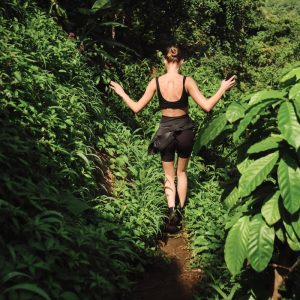 Back view of attractive girl exploring wild jungle on tropical island trekking en ilha grande